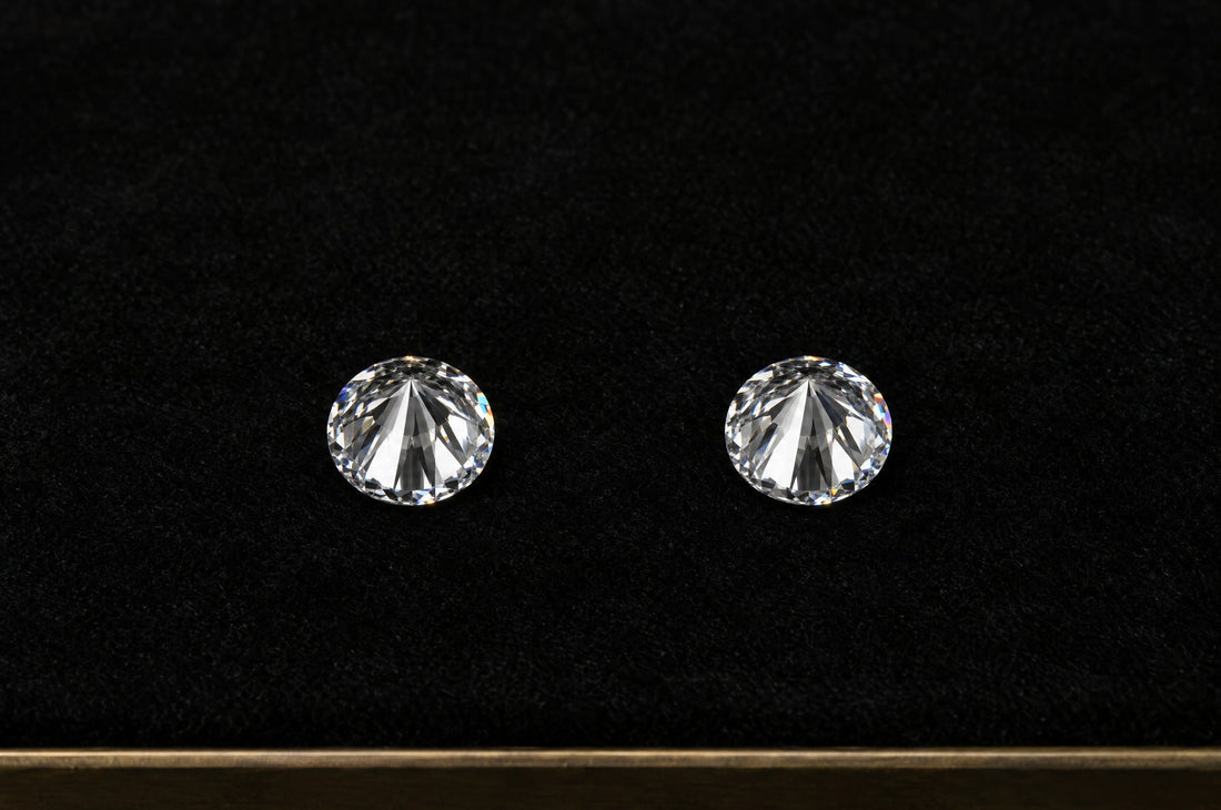Two identical round diamonds resting table-down on a black velvet grading tray